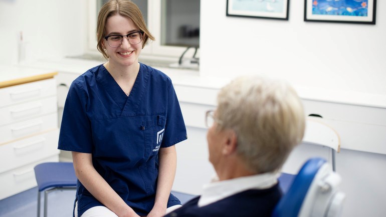 Tandvårdspersonal och äldre patient  i behandlingsrum på universitetets tandvårdsklinik. 