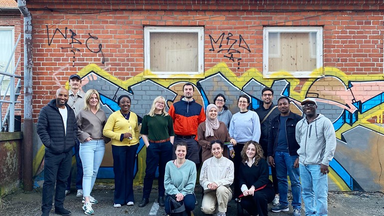 Gruppfoto på studenter framför en tegelvägg.