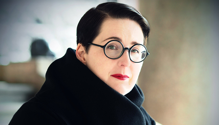Karin Tidbeck in a black coat and black round glasses.