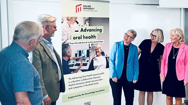 Fem personer samlade kring fanan Advancing Oral Health.