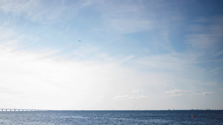 Människor badar i havet vid Ribersborg. I bakgrunden syns öresundsbron.