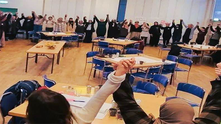 En föreläsningssal där personer sträcker upp händerna