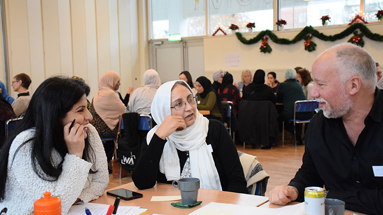 Personer i ett samtal vid ett bord.